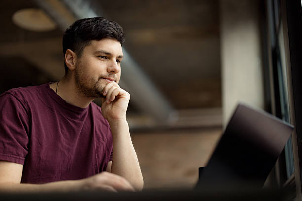 Young Man Working Outdoors on Laptop in Casual Urban Setting