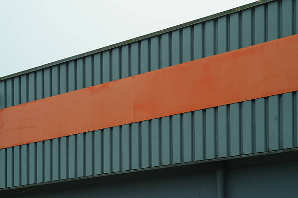 istock Orange stripe decorating a grey corrugated iron industrial building 2210887388