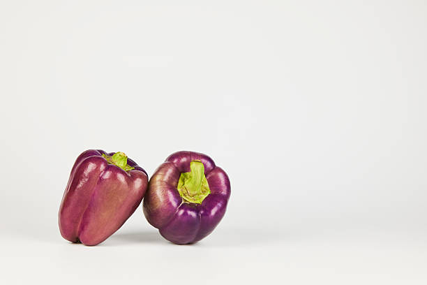 A red pepper alongside an eggplant presented on a dark minimalist background