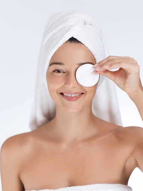 istock Smiling Woman with Towel Using Cotton Pad in Skincare Routine 2210890702