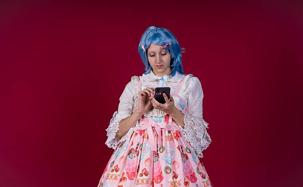 istock Cosplayer using smartphone on red background: looking down and browsing social media 2210891674