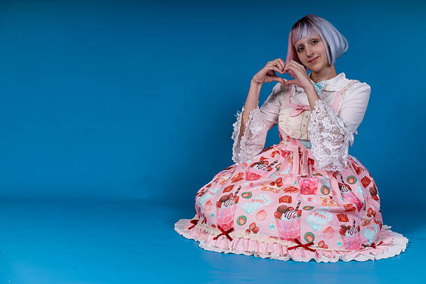 istock Young cosplayer making heart shape with hands in studio with blue background 2210894373