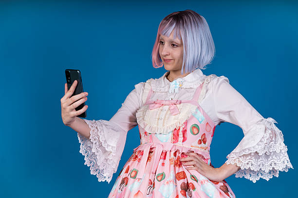 istock Young cosplayer taking a selfie with smartphone on blue background 2210894473