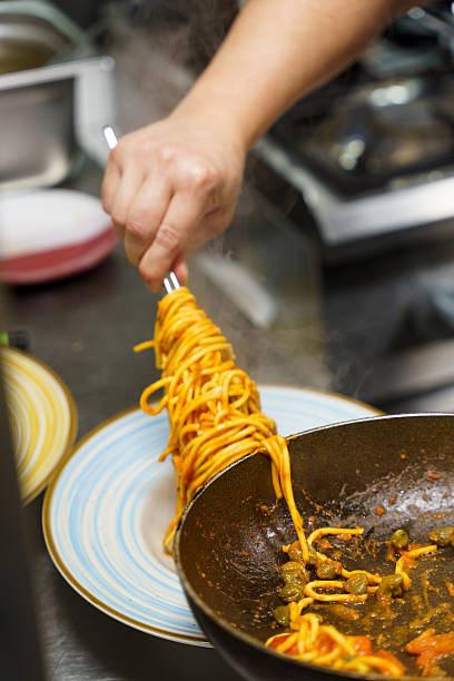 istock Chef using tongs to plate spaghetti with tomato sauce 2210895632
