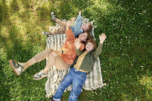 istock Joyful Mother with Two Sons on Blanket and Waving at Camera 2210899933