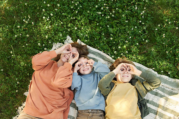 Mother and Two Boys on Blanket and Making Silly Faces Looking Up