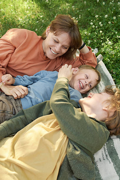 istock Two Brothers Having Fun and Smiling with Mother in Park 2210899956