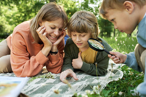 istock Mother with Two Boys Using Magnifying Glass Looking at Bugs 2210899957