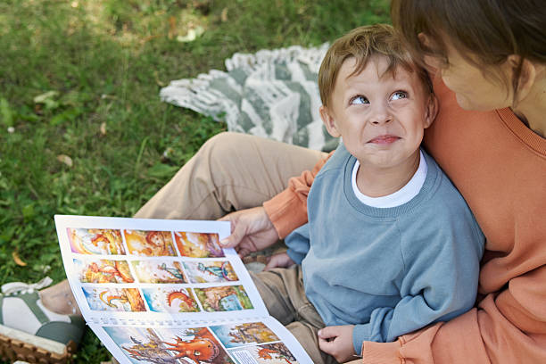 Smiling Boy on Mothers Lap Reading Book in Park