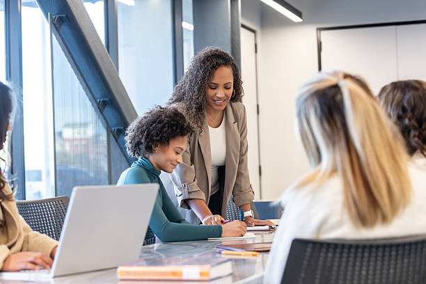 istock Teacher assists teenage student as she works on project in library 2210901523