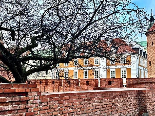 view of a fortress in Warsaw's old town with colorful buildings in the background and a bare tree on a winter day