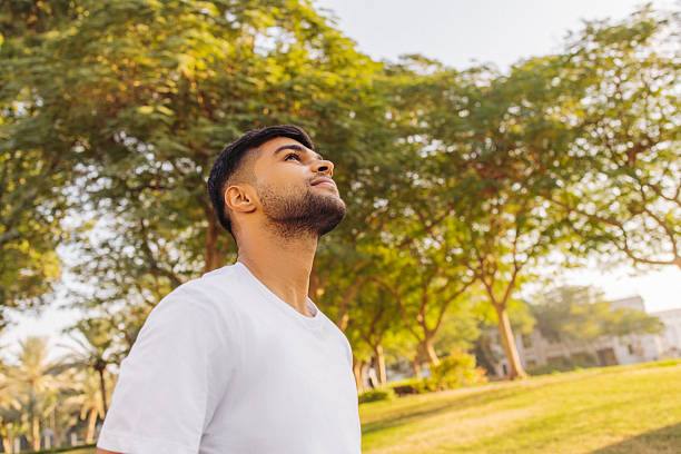 istock Young man outdoors enjoying the sunshine and surrounded by greenery 2210905128