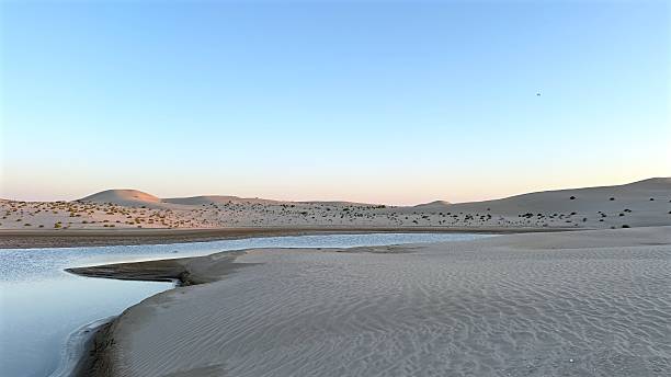 istock Abu Dhabi, UAE - March 23, 2025:Desert cliffs hold salty lake with deep erosion lines visible across desert edges, lake surface contrasts dry salty sediment, showing lake uniqueness at sunset. 2210906847
