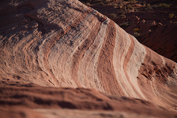 This breathtaking photo captures the intricate layers and patterns of ancient sandstone rock formations in Valley of Fire State Park, Nevada. The undulating lines and varying shades of red, orange, and pink are the result of wind and water erosion over millions of years, painting a stunning canvas across the rugged desert landscape.