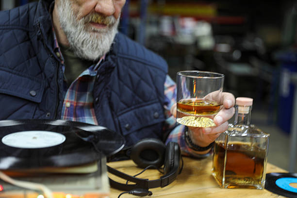 Glass of whiskey with smoking cigar on dark wooden table