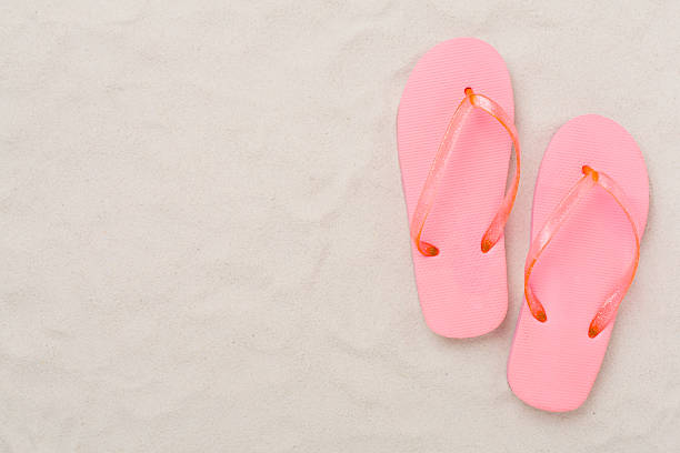 Woman relaxing on a pebble beach with pink water shoes, enjoying the sea view