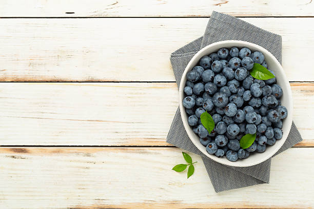 istock Bowl with fresh bright blueberries on wooden background,top view 2210918472
