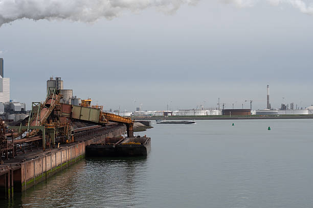rotterdam harbor, netherlands - april 17, 2025 : cargo berge loading with iron ore from a industrial facility of the port with indurial storage surroundings