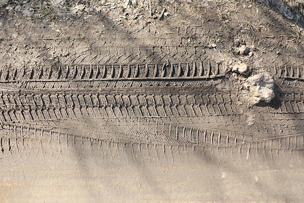 This is a closeup view of tire tracks that are imprinted on a dirt surface, highlighting intricate details and texture