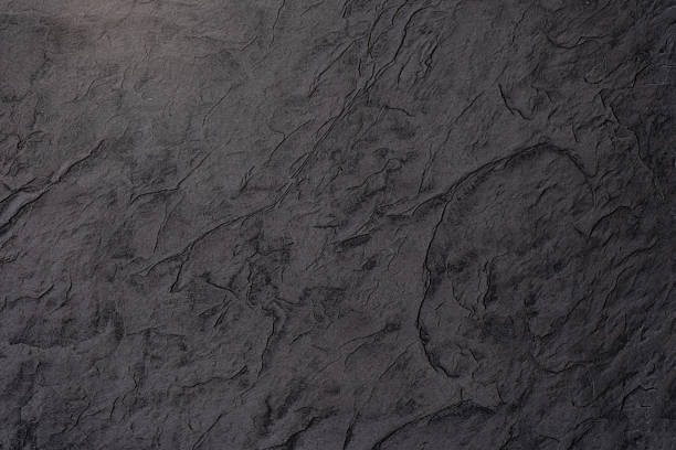 Textured dark surface resembling natural stone with intricate patterns and shadows.