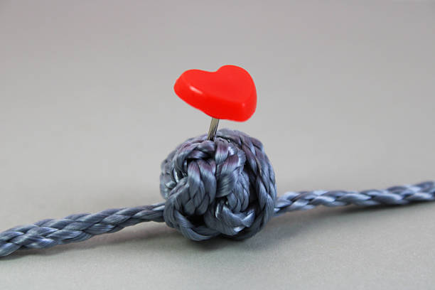 Thumbtack with a heart marking a knot, a solution to a conflict