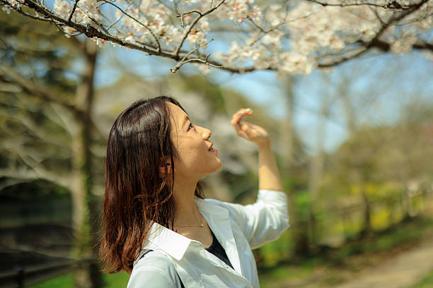istock Young beautiful woman enjoying cherry blossoms 2210958235