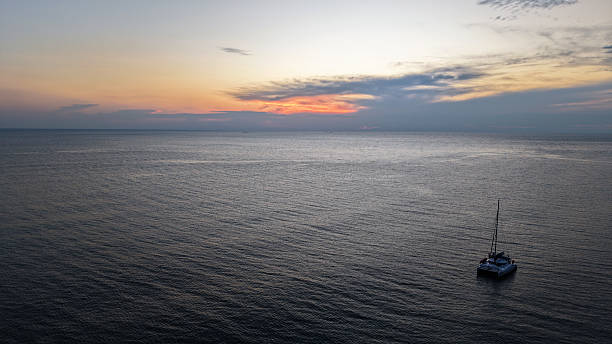istock Catamaran sailing in calm sea at sunset with cloudy sky 2210958283