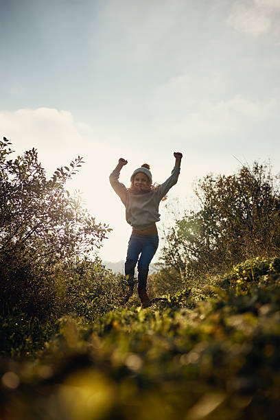 Little girl happily runs across a huge green summer field. Concept of an active healthy child
