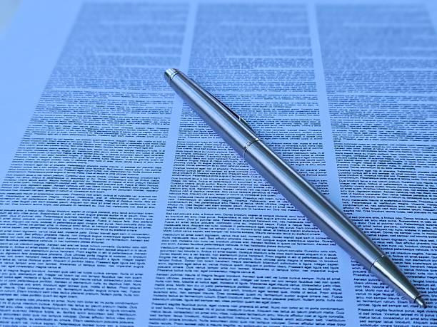 istock Metal pen resting on a sheet of detailed text on a document table 2210962456