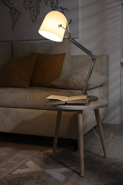 istock Stylish night lamp and book on side table near sofa in room. Interior design 2210966544