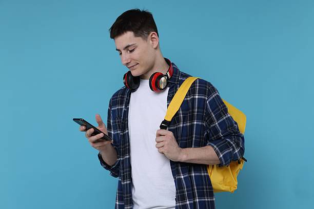 istock Student with backpack, smartphone and headphones on light blue background 2210966723