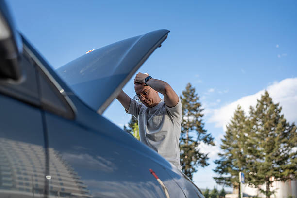 istock Man Inspecting Car Engine on a Clear Day in Outdoor Setting 2210969227