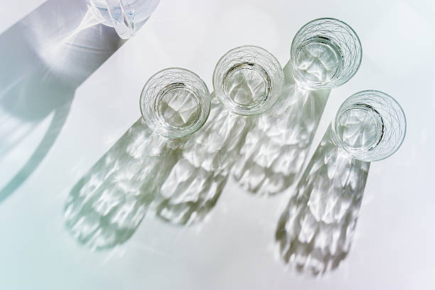 istock Water Glasses and water jug with Shadows and sunlight Reflection on white background, colored photo minimal style, aesthetic summer still life, refraction throug crystal shine cups, caustics 2210969734
