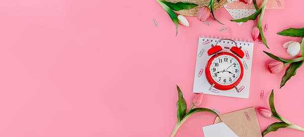 istock A beautiful flat lay with a notepad with an alarm clock and flowers on a pink isolated background, the place of the original text 2210970679