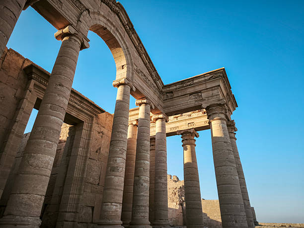 Ancient stone ruins with tall columns and a central doorway under a clear blue sky.