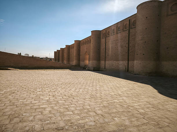 Ancient brick fortress wall with round towers under a clear blue sky.
