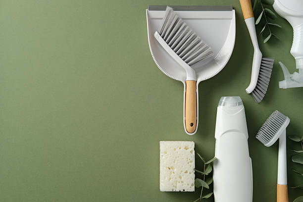 istock Flat lay of essential cleaning tools: dustpan, brushes, sponge, spray bottle, and detergent on a clean green background. Perfect for home cleaning, housekeeping, and hygiene concepts. 2210974704