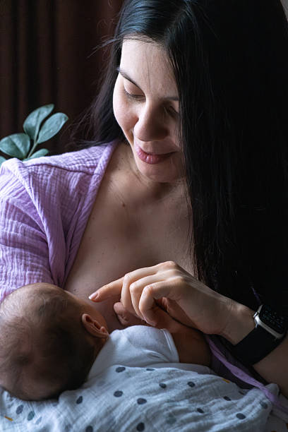 istock Mother Breastfeeding Baby by Window 2210975206