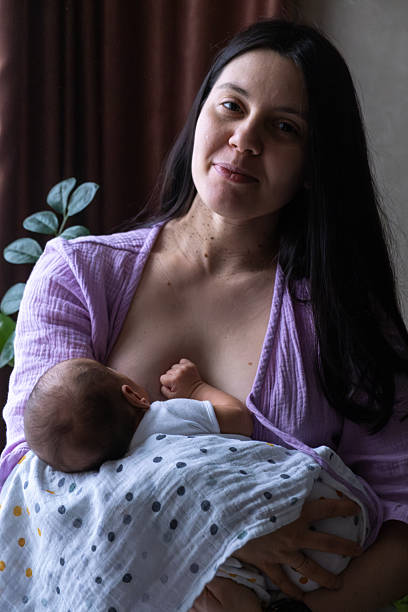 istock Mother Breastfeeding Baby by Window 2210975208