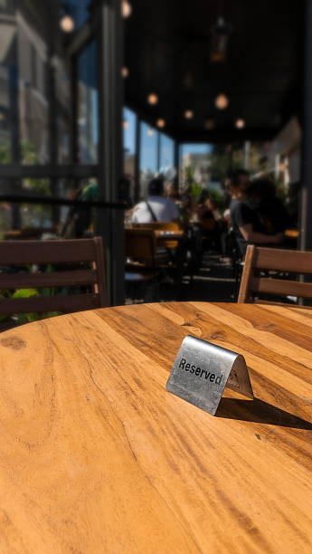 istock Table Reserved Sign Closeup Sunny Outdoor Cafe Setting Brown Silver 2210976221