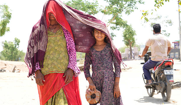 Beawar, Rajasthan, India, April 15, 2025: A woman with her daughter covers themselves with a scarf for protection from the sun amid scorching heat on a hot summer day in Beawar.
