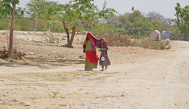 Beawar, Rajasthan, India, April 15, 2025: A woman with her daughter covers themselves with a scarf for protection from the sun amid scorching heat on a hot summer day in Beawar.