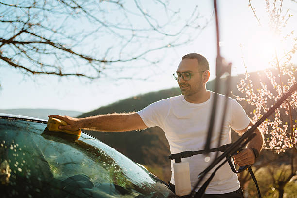 istock Young Man Washing Car Windshield Outdoors on a Sunny Day in Spring 2210981206