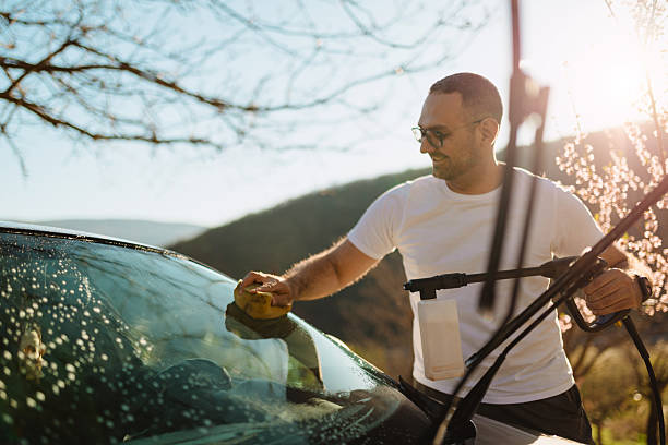 istock Young Man Washing Car Windshield Outdoors on a Sunny Day in Spring 2210981214