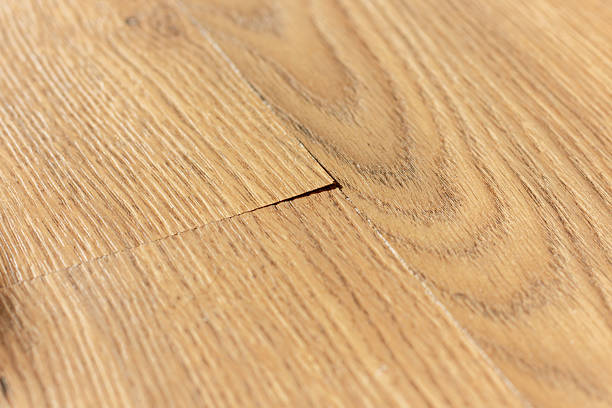 istock Section of laminate flooring with improperly installed, showcasing a noticeable protrusion at the seams where the planks meet. 2210983225