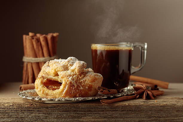 Viennese strudel and black coffee on an old wooden table. Fresh baked goods with anise and cinnamon, sprinkled with powdered sugar.