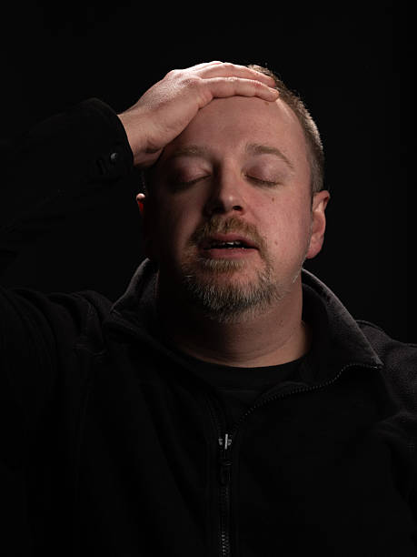 istock Man Showing Concern with Hand on Forehead Against Dark Background 2210993388