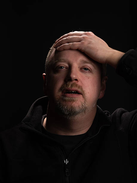 istock Man Showing Concern with Hand on Forehead Against Dark Background 2210993390