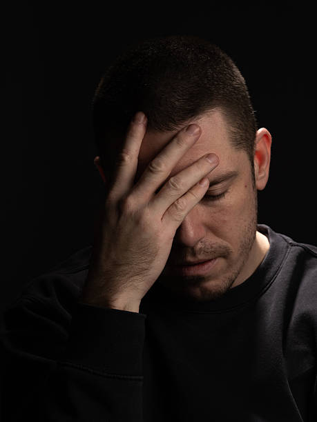 istock Man Showing Concern with Hand on Forehead Against Dark Background 2210994000