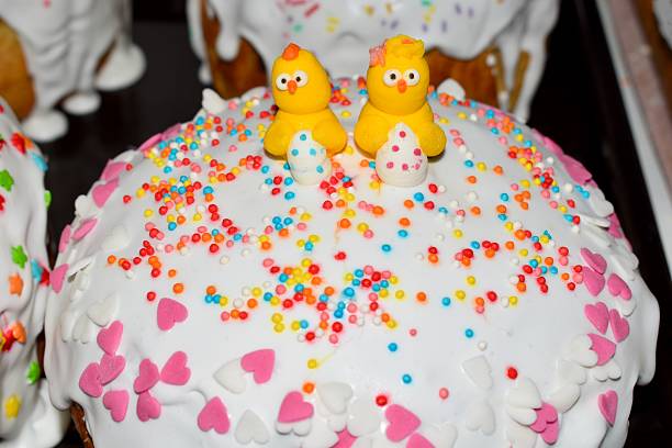 Classic Easter cake with fluffy white meringue frosting, colorful sprinkles, and two cute yellow chicks on top. Festive homemade holiday dessert with bright seasonal decoration. Close-up.